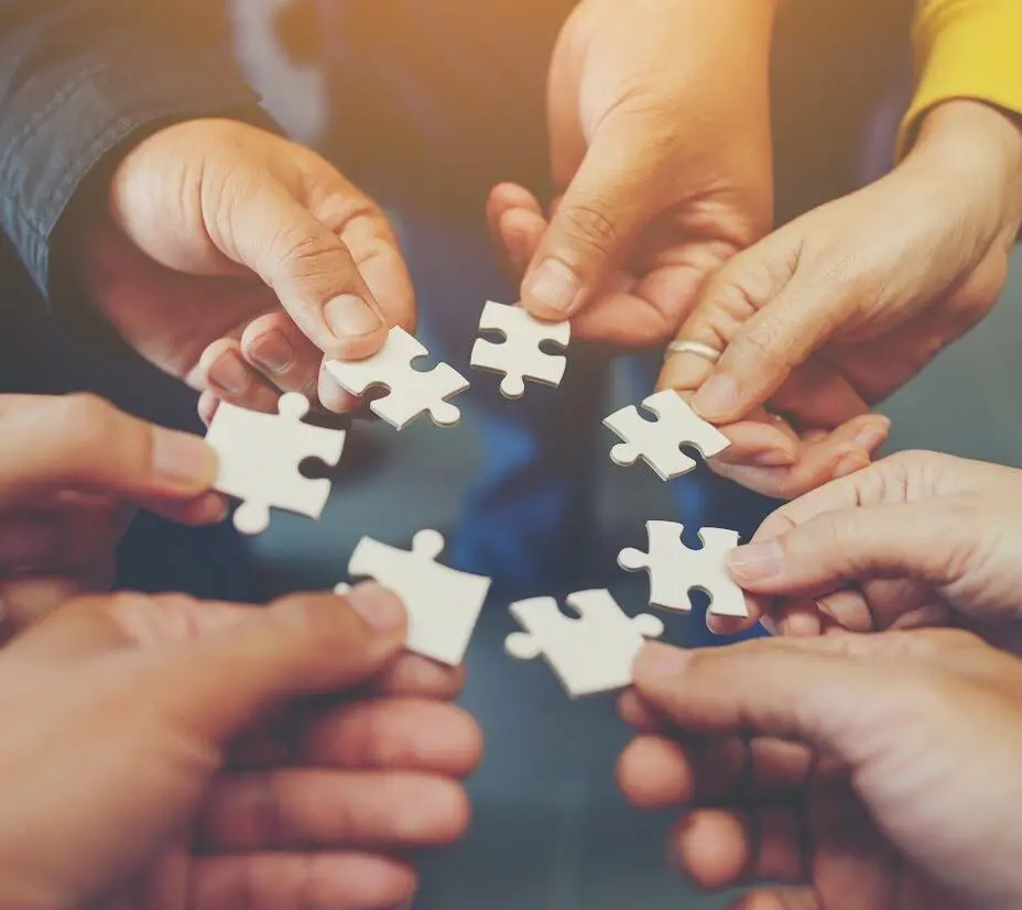Hands holding puzzle pieces together.
